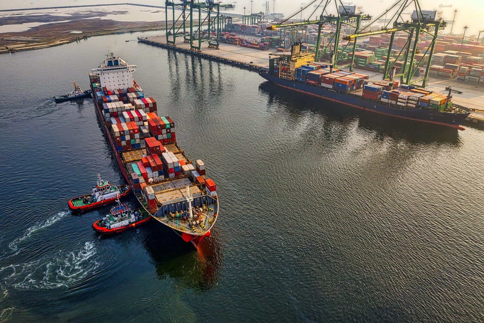 Ocean freight container vessel with tugboat at sea